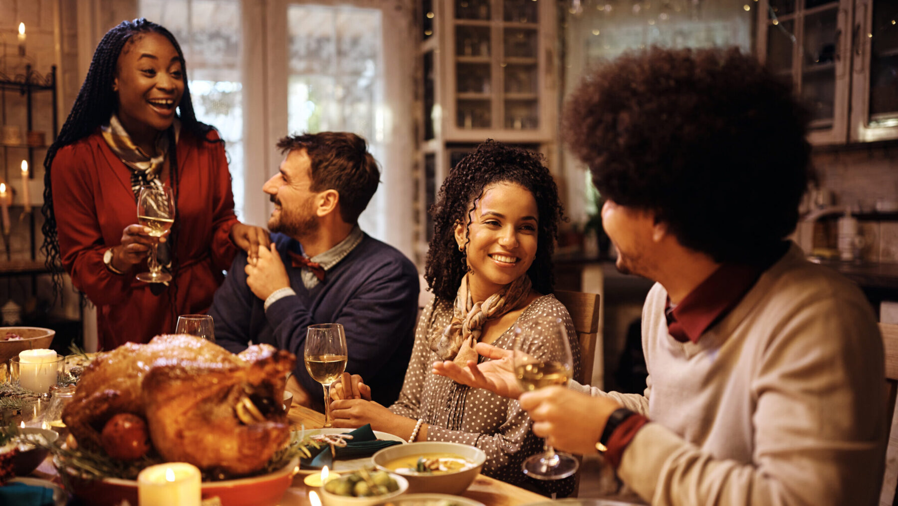 A group of people gather for conversation around a table filled with food.