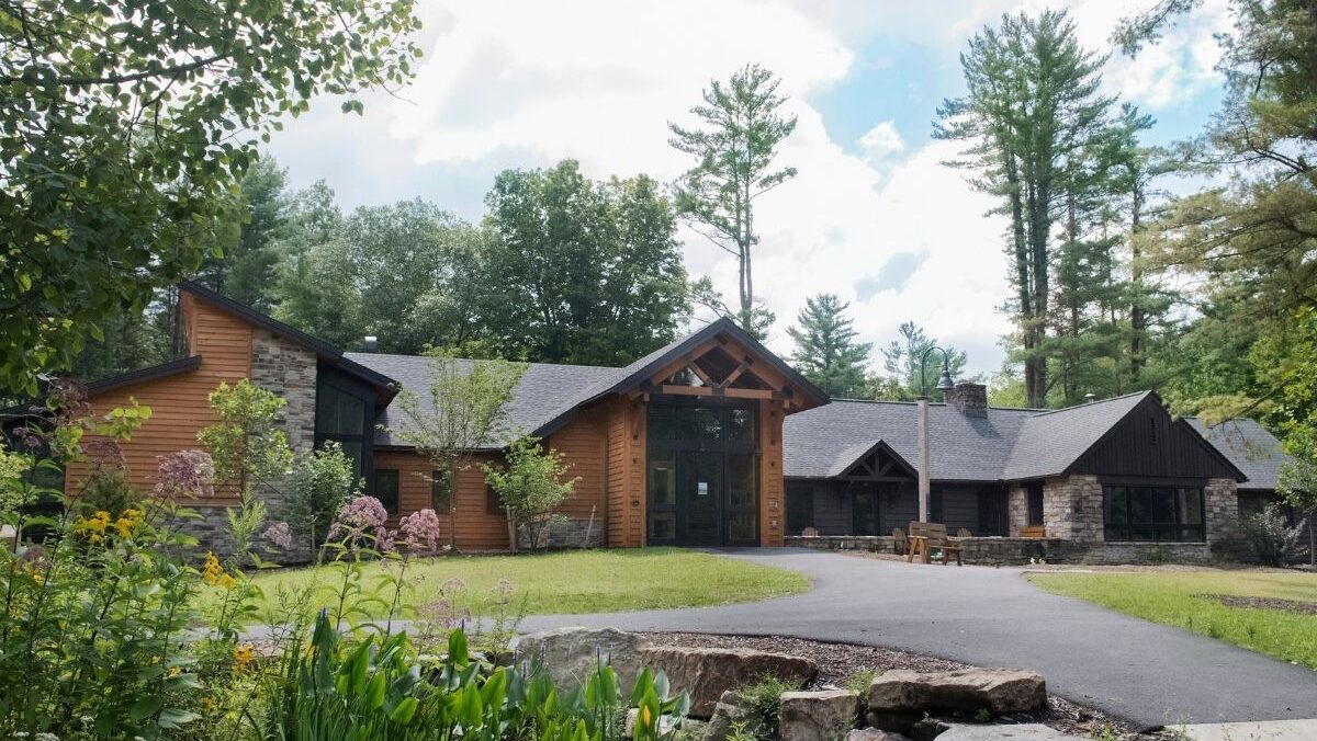 A view across a small frog pond, looking toward the entrance of the visitor center at Shaver's Creek Environmental Center.