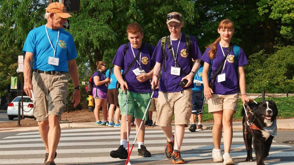 A counselor leads a group of visually impaired participants on a walk
